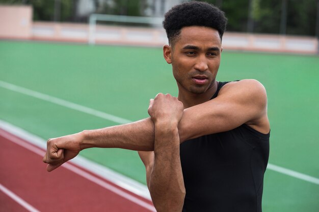 Homem bonito atleta Africano fazer exercícios de alongamento