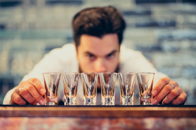 Homem bonito barman fazendo beber e cocktails num balcão