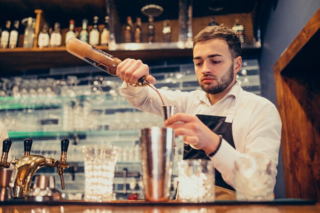 Homem bonito barman fazendo beber e cocktails num balcão