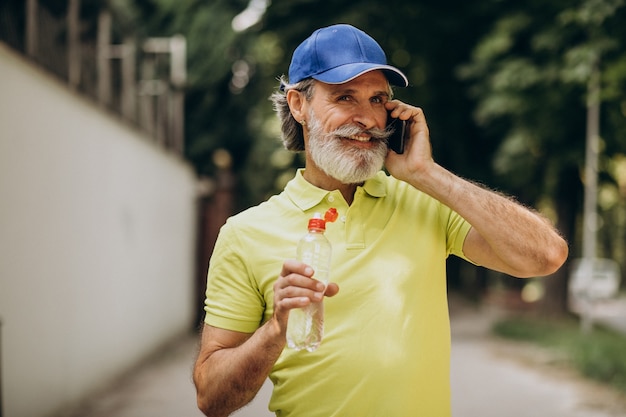 Homem bonito bebendo água no parque depois de correr