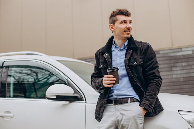 Homem bonito, bebendo café em seu carro