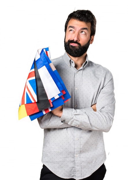 Homem bonito com barba segurando muitas bandeiras e pensando