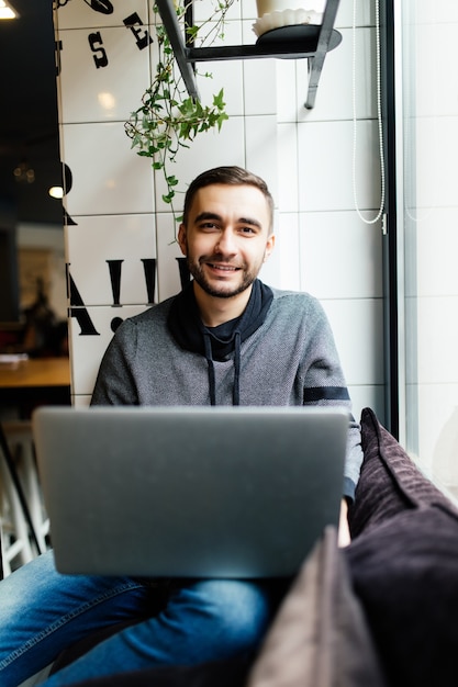 Homem bonito com laptop em um café