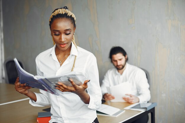 Homem bonito com uma camisa branca. Mulher africana com parceiro. Cara com um laptop.