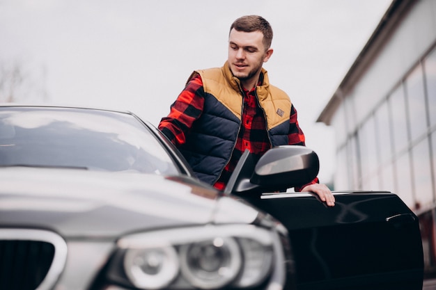 Homem bonito, de pé ao lado do carro