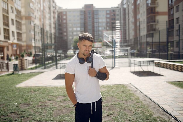 Homem bonito, de pé em um parque com fones de ouvido