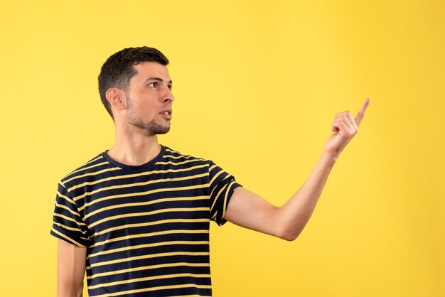 Homem bonito de vista frontal em uma camiseta listrada preto e branco em pé sobre fundo amarelo isolado