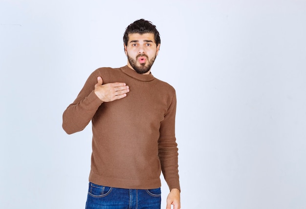 Homem bonito descansando a mão em seu coração e olhando para longe foto de alta qualidade