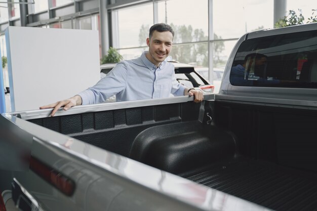 Homem bonito e elegante em um salão de automóveis