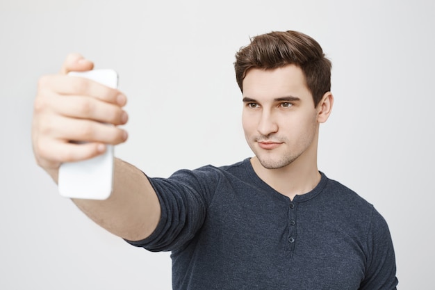 Homem bonito e elegante tirando selfie para redes sociais no smartphone