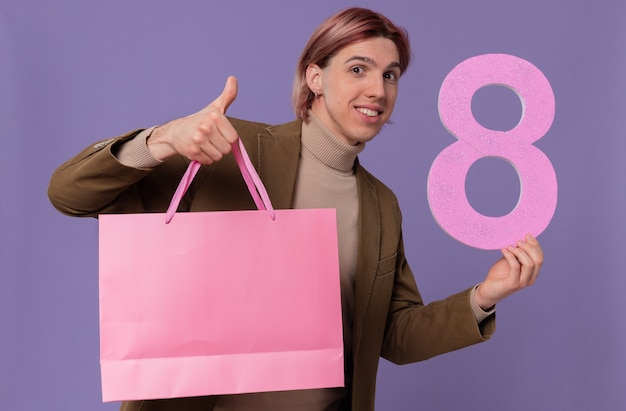 Homem bonito e sorridente segurando uma sacola de presente rosa e número oito segurando