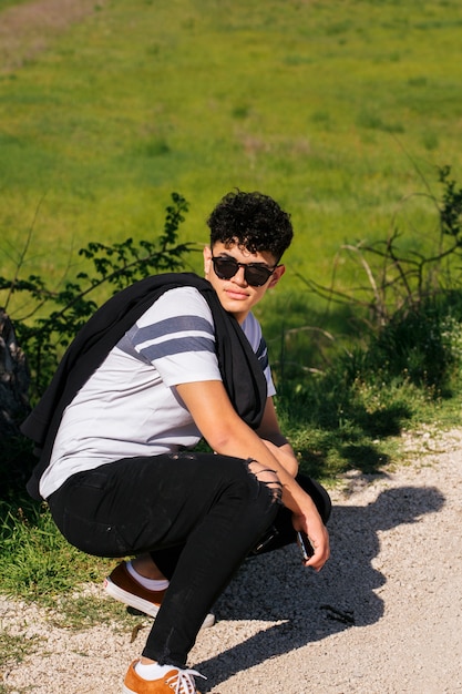 Homem bonito elegante usando óculos e posando no caminho