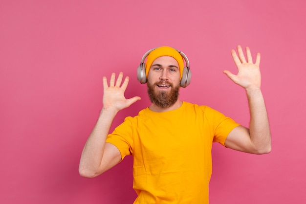 Homem bonito em dança casual com fones de ouvido isolados em fundo rosa