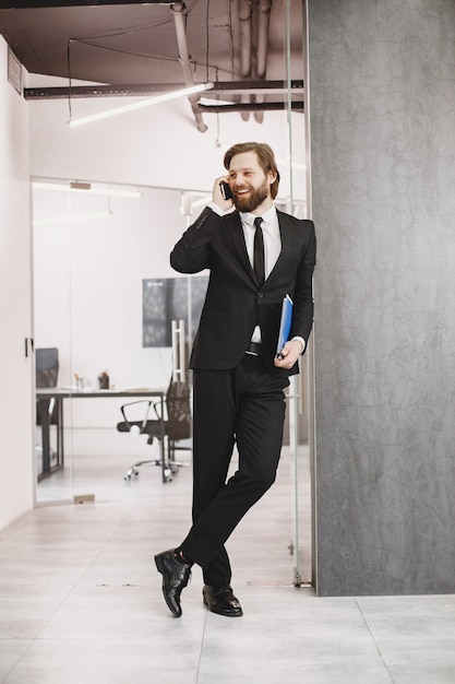 Homem bonito em um terno preto. Empresário com telefone celular.