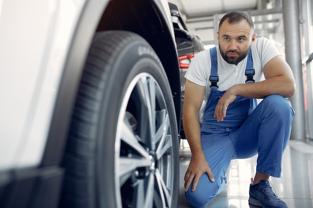 Homem bonito em um uniforme azul verifica o carro