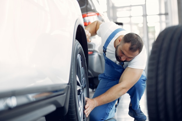 Homem bonito em um uniforme azul verifica o carro