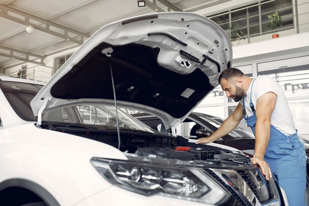 Homem bonito em um uniforme azul verifica o carro