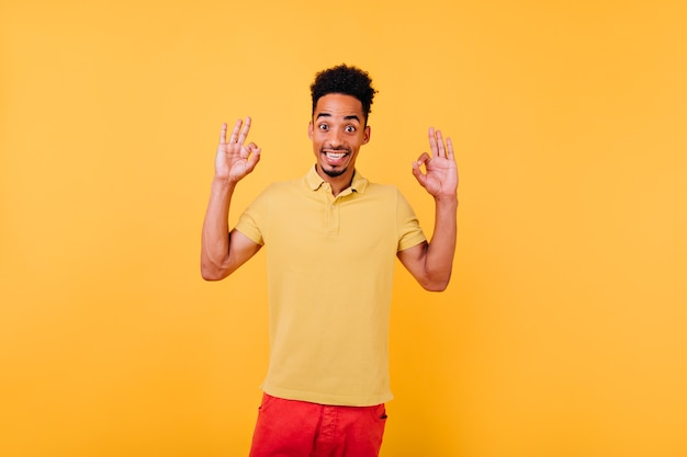 Homem bonito espantado em posar de camiseta de verão. Retrato de cara animado com cabelo preto.