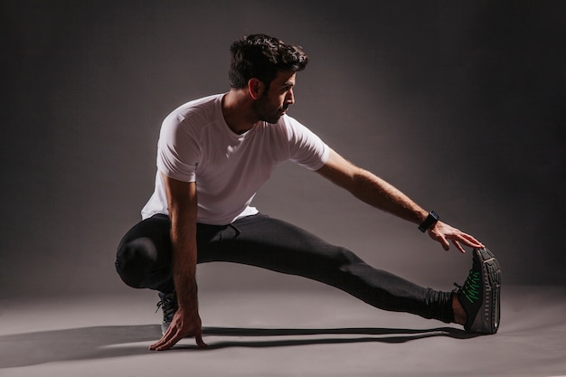 Foto grátis homem bonito, exercitando-se no estúdio escuro