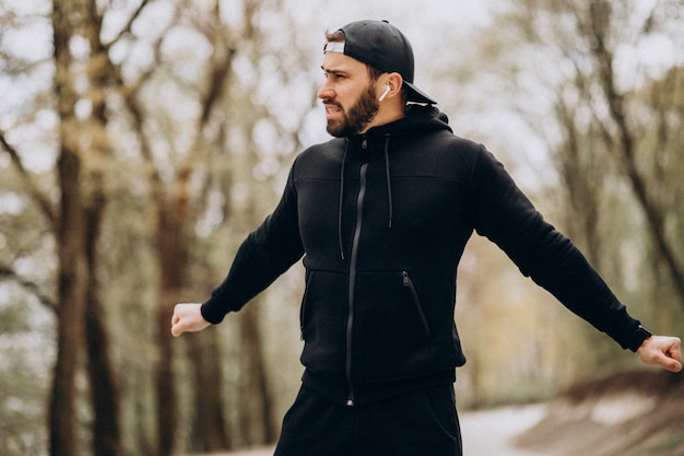 Homem bonito, exercitando-se no parque em roupas esportivas