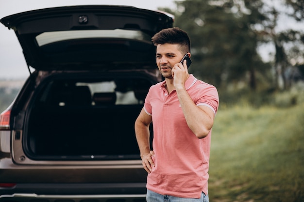 Homem bonito, falando ao telefone ao lado do carro