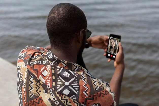 Homem bonito fazendo uma videochamada com smartphone moderno ao ar livre