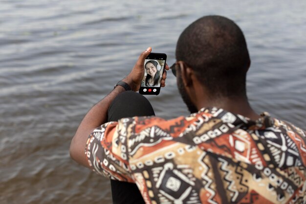 Homem bonito fazendo uma videochamada com smartphone moderno ao ar livre