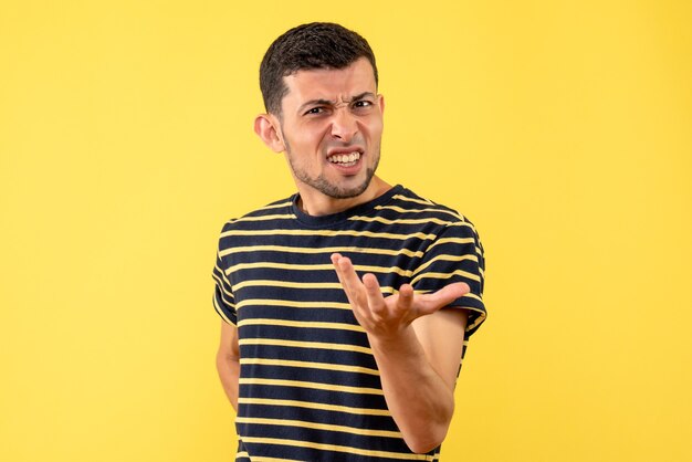 Homem bonito insatisfeito de frente em camiseta listrada preta e branca com fundo amarelo