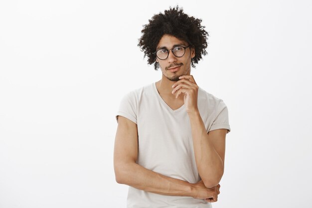 Homem bonito intrigado sorrindo, parecendo interessado, fazendo uma escolha