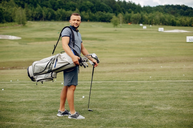 Homem bonito, jogando golfe em um campo de golfe