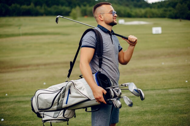 Homem bonito, jogando golfe em um campo de golfe