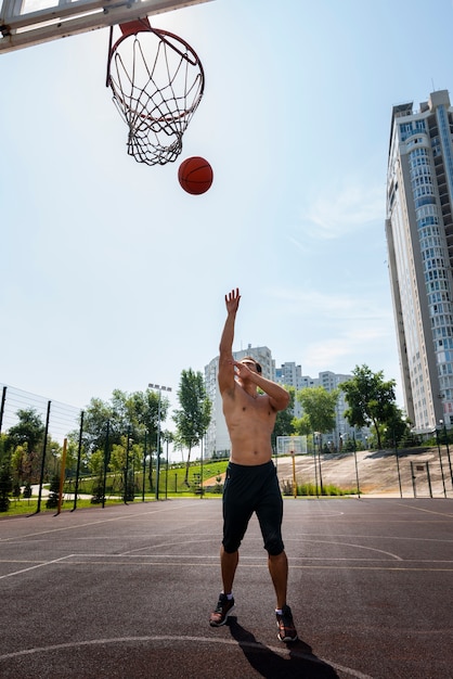 Homem bonito, jogando uma bola tiro no escuro