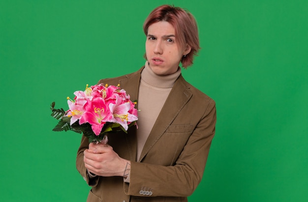 Homem bonito jovem ansioso segurando um buquê de flores e olhando