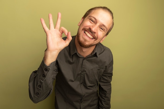 Foto grátis homem bonito jovem feliz com camisa cinza mostrando sinal de ok sorrindo