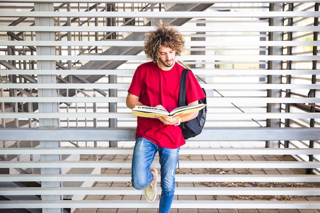 Homem bonito lendo livro perto da parede