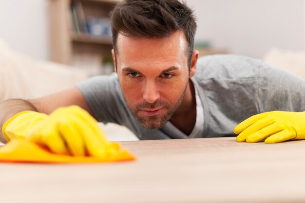 Homem bonito limpando manchas da mesa