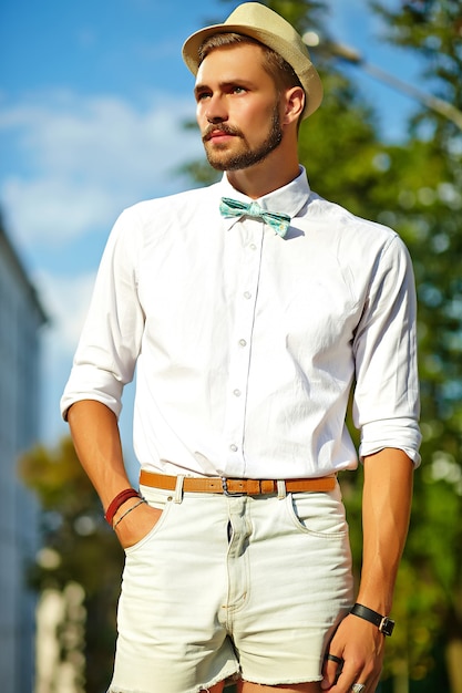 Homem bonito modelo hipster em roupas de verão elegante posando de chapéu