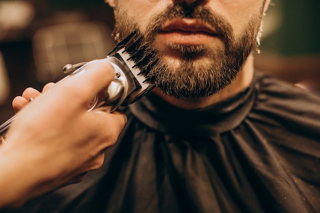 Homem bonito na barbearia barbeando a barba
