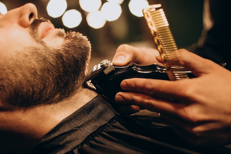 Homem bonito na barbearia barbeando a barba