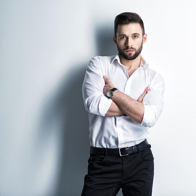 Foto grátis homem bonito na camisa branca e calça preta - posando cara atraente com penteado da moda. homem confiante com barba curta. menino adulto elegante com cabelo castanho.