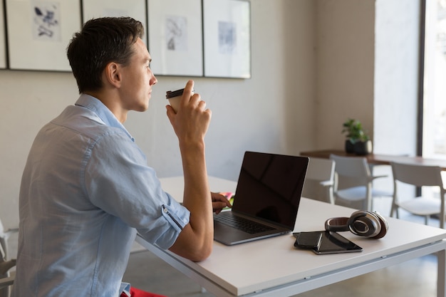 Homem bonito ocupado com seu trabalho tomando café