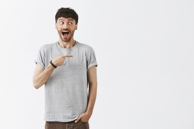 Homem bonito parecendo feliz e apontando para a direita