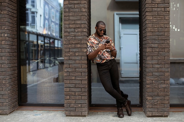 Foto grátis homem bonito passando um tempo ao ar livre usando um smartphone moderno