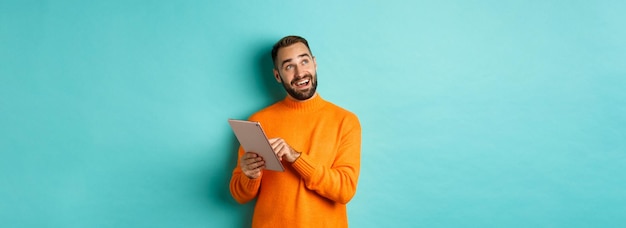 Homem bonito pensando e usando tablet digital comprando online e pensando em ideias olhando para cima