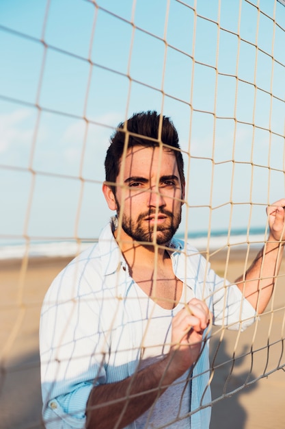 Foto grátis homem bonito perto de rede de vôlei