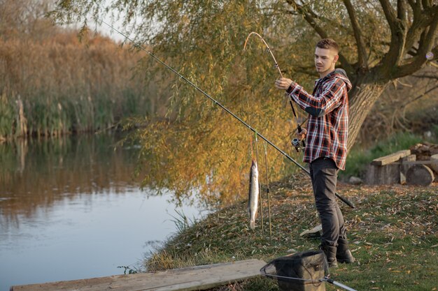 Homem bonito perto do rio em uma manhã de pesca
