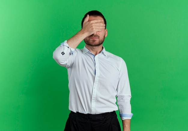 Foto grátis homem bonito satisfeito fecha os olhos com a mão isolada na parede verde