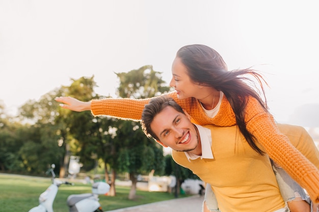 Homem bonito se divertindo em um encontro com uma mulher feliz com cabelo castanho acenando