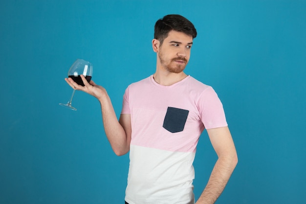 Homem bonito, segurando a taça de vinho e olhando para longe.