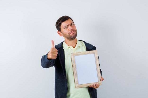 Homem bonito segurando uma moldura em uma roupa casual